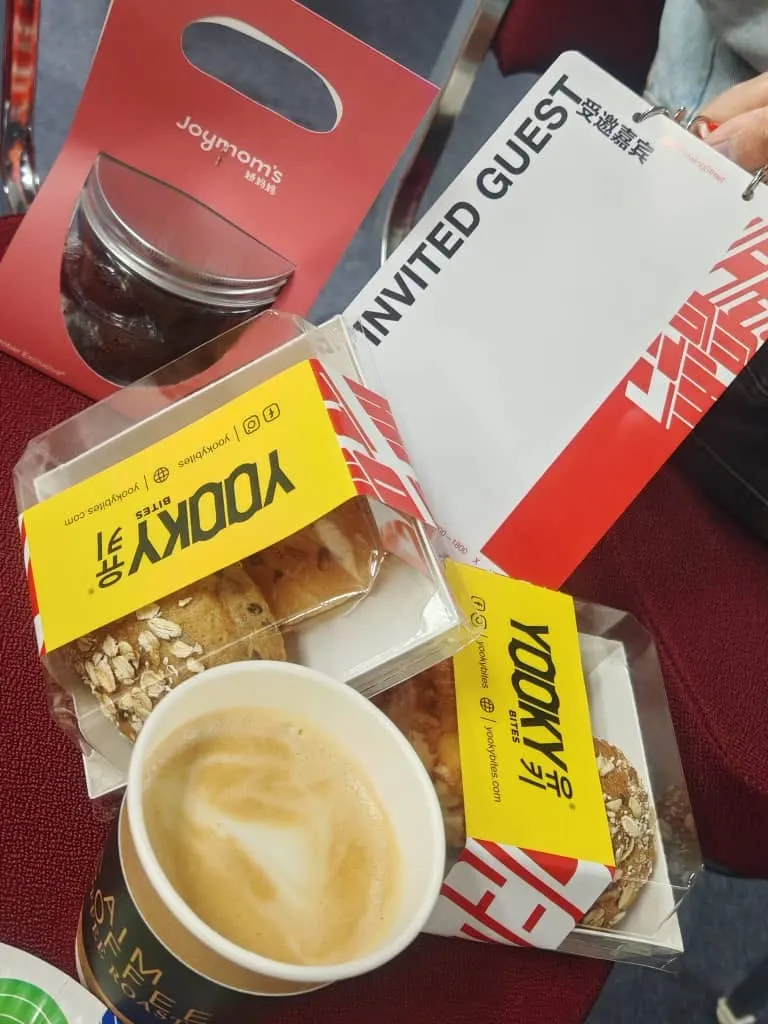 Boxed buns and a paper cup of coffee beside an invited guest pass at TEDxPetalingStreet 2024
