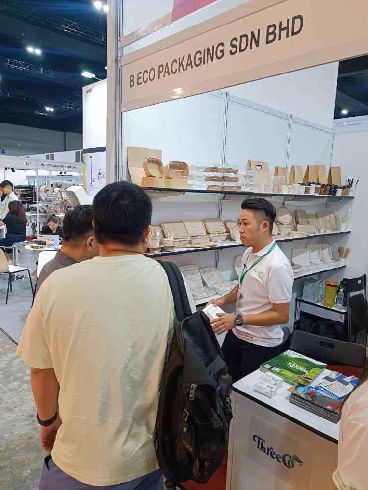 Wakil B Eco Packaging menerangkan produk kepada dua pengunjung di gerai