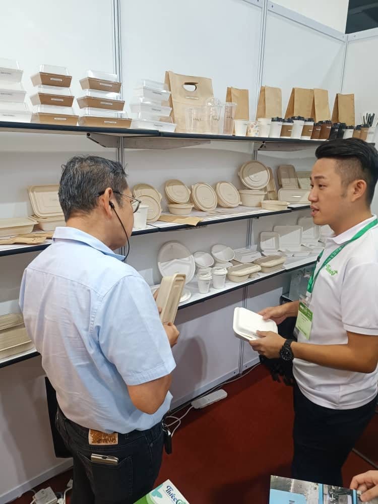 Ahli pasukan B Eco Packaging menghulurkan kotak hampas tebu kepada pengunjung untuk dilihat lebih dekat