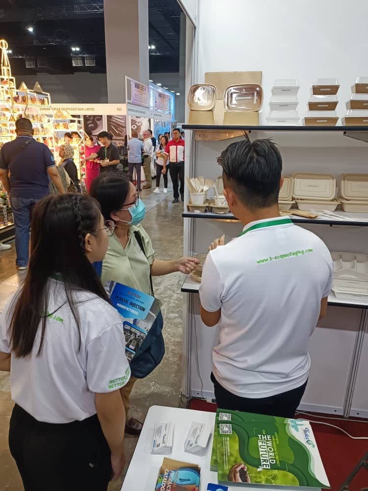 Pengunjung memeriksa pinggan mangkuk hampas tebu dan alat makan kayu bersama kakitangan B Eco Packaging di gerai